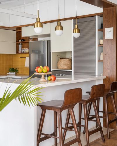 Kitchen with mustard tile backsplash, brass pendants, wood stools at island counter