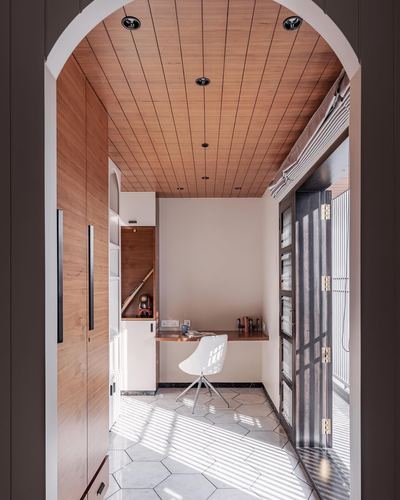 Arched wood-panelled corridor leading to a built-in desk lit by patterned window light