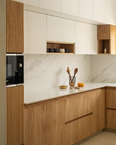 Wood-toned kitchen with fluted panelling, marble-look backsplash, and built-in microwave niche