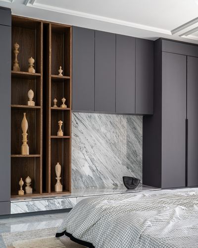 Bedroom wall with dark cabinetry, marble backsplash, and wooden display shelves holding turned wood finials