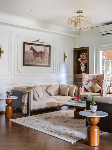 Cream-paneled living room with horse painting, crystal chandelier, wingback chair and herringbone floor