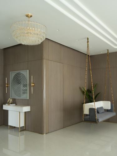 Foyer with wood-panelled walls, crystal chandelier, console table, and a hanging swing bench