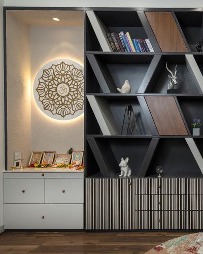 Pooja niche with backlit mandala om art beside a dark geometric display shelf unit
