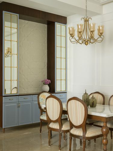 Dining room with brass chandelier, striped oval-back chairs, and blue-grey cabinetry flanking a textured wall panel