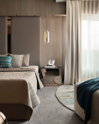 Bedroom with fluted wood panel, mirrored nightstand, teal-accented bedding and round rug