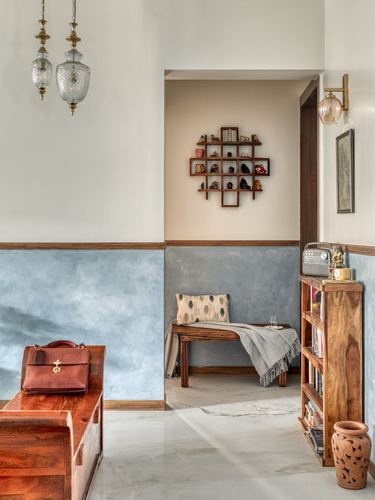 Foyer with blue lime-plastered dado, wooden bench, bookshelf, and hanging glass pendant lamps