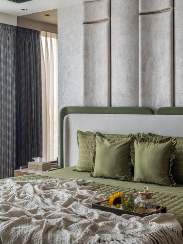Bedroom with olive green bedding, curved padded headboard, and channel-tufted textured wall panel