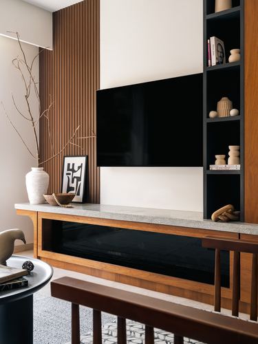 TV console wall with wood fluting, terrazzo ledge, dark shelving and ceramic decor
