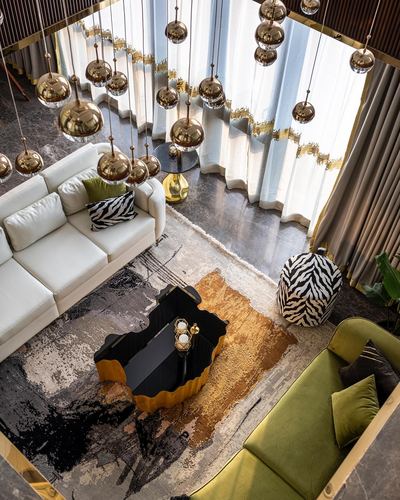 Overhead view of luxury living room with brass pendant cluster, sculptural coffee table and zebra pouf