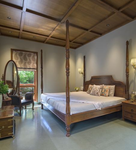 Teak four-poster bed under coffered wooden ceiling in a traditional-style bedroom
