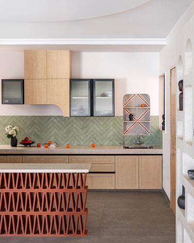 Kitchen with green herringbone tile, wood cabinetry, and terracotta jali island base