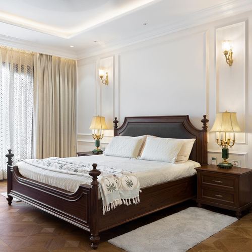 Neo-classical bedroom with dark wood four-poster bed, cream wainscoting, and brass sconces