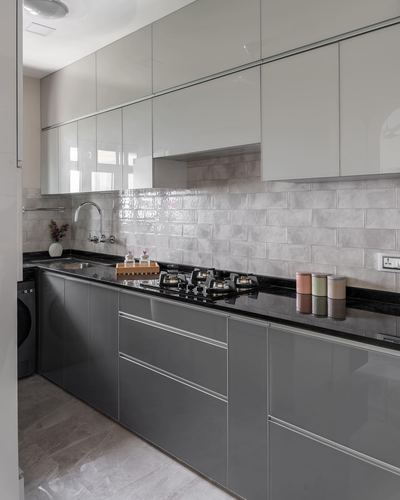 L-shaped modern kitchen with glossy grey cabinets, black countertop and handmade-look tile backsplash