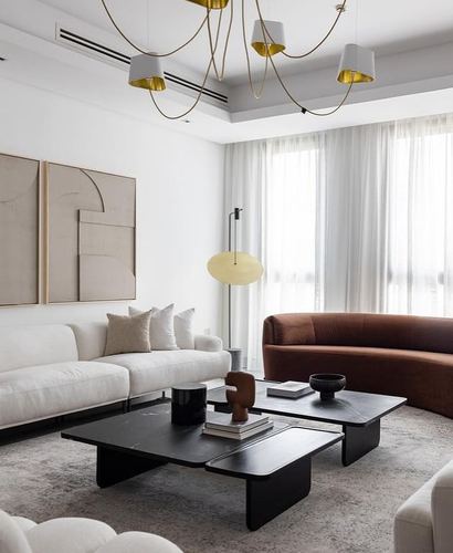 Modern living room with curved terracotta sofa, black stone coffee tables, and gold pendant lights