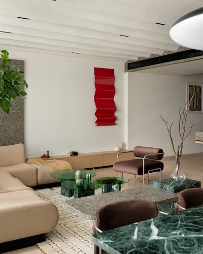 Living room with beige sofa, green marble tables, and red wall sculpture