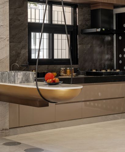 Kitchen island with gold basin sink under a teardrop pendant, dark stone backsplash behind
