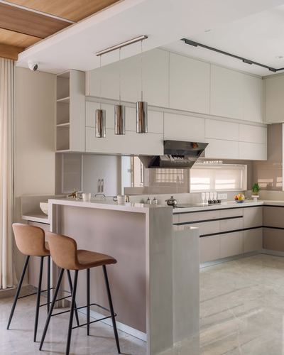 Modern beige kitchen with island, cylindrical pendant lights, and tan leather bar stools