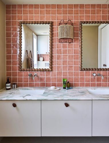 Double vanity bathroom with terracotta zellige tile, scalloped mirrors, and green-veined marble countertop
