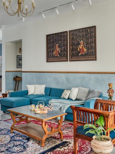 Living room with teal sectional sofa, wooden coffee table, framed folk art panels above