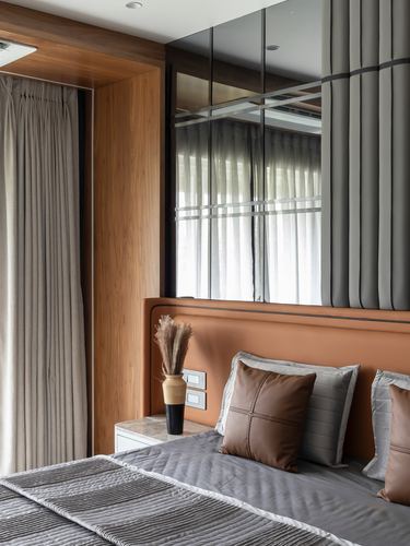 Bedroom corner with tan leather headboard, mirrored wall, and wood-framed curtain nook