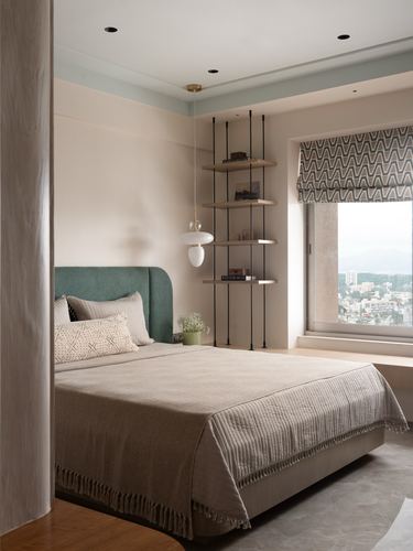 Bedroom with teal upholstered headboard, layered bedding, hanging shelf and city view window