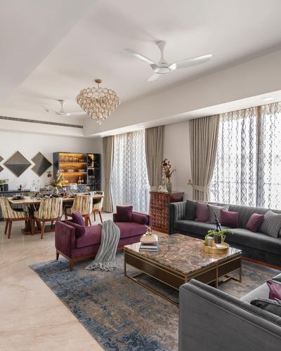 Open living room with grey sectional sofa, plum velvet chaise, marble coffee table and layered curtains