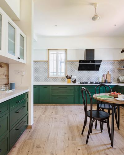 Green cabinetry kitchen with patterned tile backsplash, wood floor, and round breakfast table