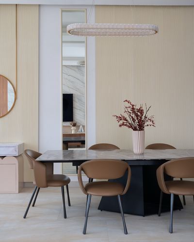 Dining room with marble table, camel leather chairs, oval bead chandelier and fluted cream walls