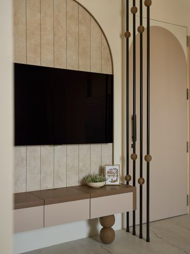 Arched fluted wood panel behind a mounted tv beside a black rod-and-bead partition screen