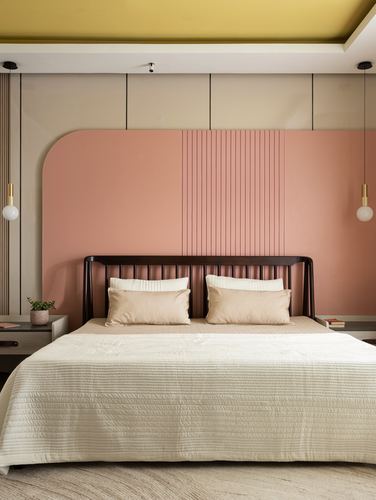 Bedroom with dark spindle bed against pink arched fluted panel wall and mustard ceiling
