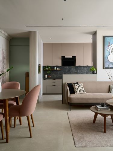 Open living and kitchen area with blush cabinetry, dark stone backsplash, and pink velvet furniture