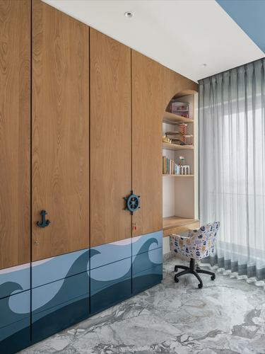 Kid's bedroom wardrobe with wave mural and anchor handles beside an arched study nook