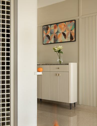 Beige fluted console with vase and geometric art in a minimalist foyer