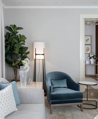 Living room corner with blue velvet armchair, cylinder floor lamp, and fiddle leaf fig against grey walls