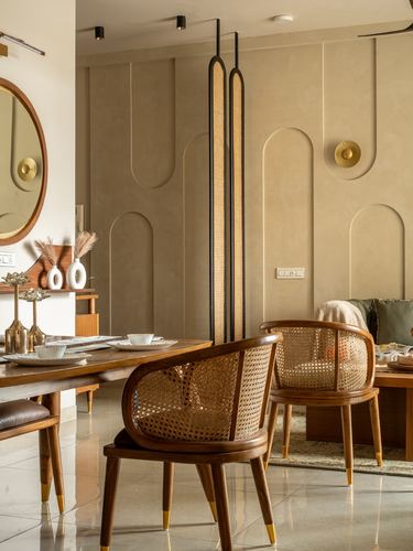 Dining area with cane-back wooden chairs, tall pendant lamps, and arched textured wall panelling.