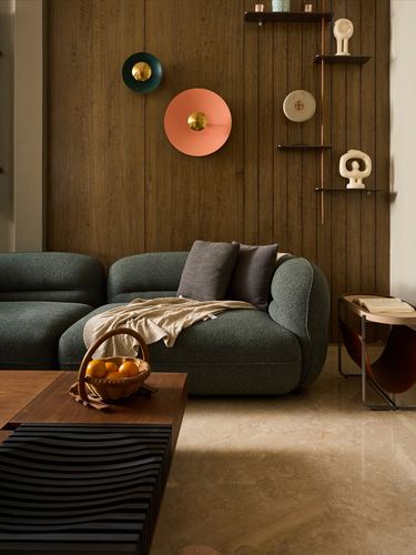 Green boucle sofa against wood-paneled wall with sculptural shelf and colorful wall discs