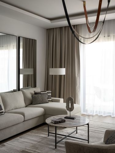 Neutral-toned living room with sectional sofa, round marble coffee table, and sheer curtains