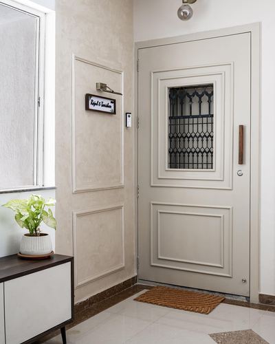 Beige paneled front door with wrought-iron grille window in a marble-floored foyer