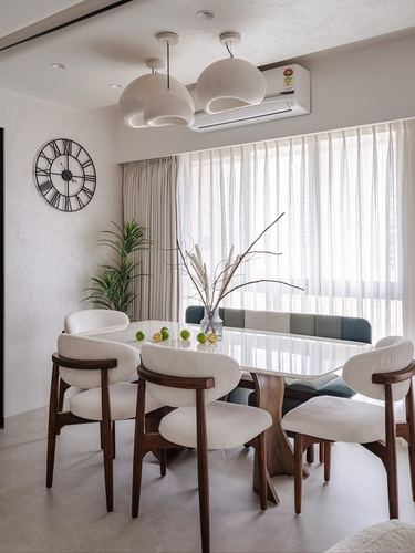 Dining room with round marble table, boucle chairs, sculptural pendant lights and city view