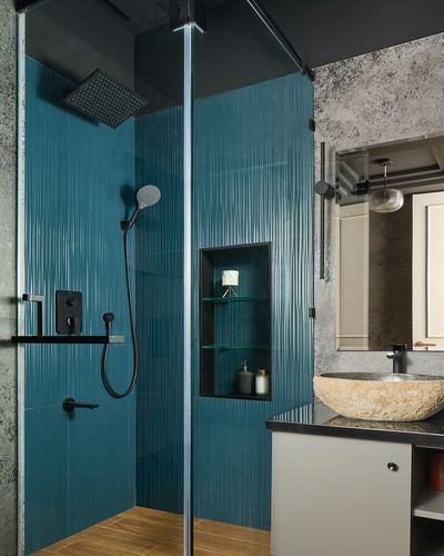 Walk-in shower with fluted teal tiles beside a stone vessel sink vanity