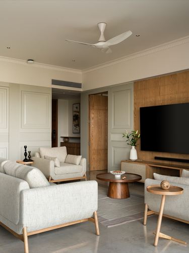 Living room with beige sofas around a round wood table, wood-panelled tv wall, sage wainscoting