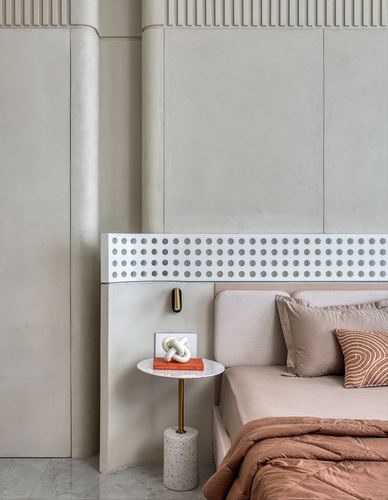 Bedroom corner with perforated headboard panel, terrazzo side table, and terracotta bedding