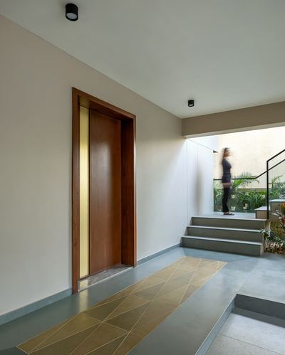 Entry foyer with wooden door, brass inlay, and stone steps leading outside as a figure walks up
