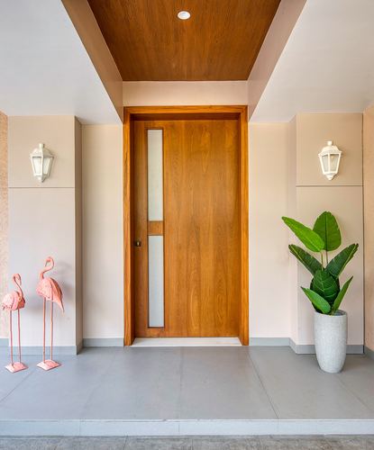 Entrance foyer with wooden door, frosted glass strip, flanking sconces, planter and flamingo figurines