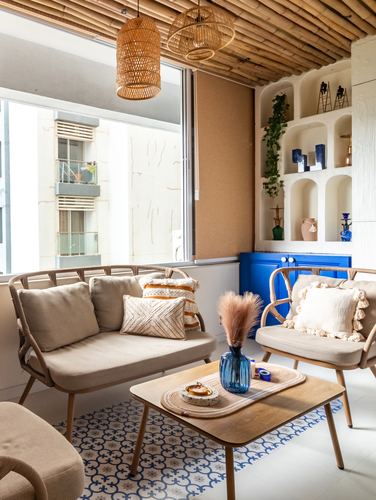 Balcony sitting area with rattan furniture, bamboo ceiling, and niche shelving in cobalt cabinet wall