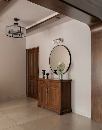 Foyer with round mirror, brass sconce, and wooden console under a curved archway