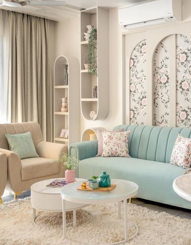 Pastel living room with mint velvet sofa against floral arched wall panels and round nesting tables