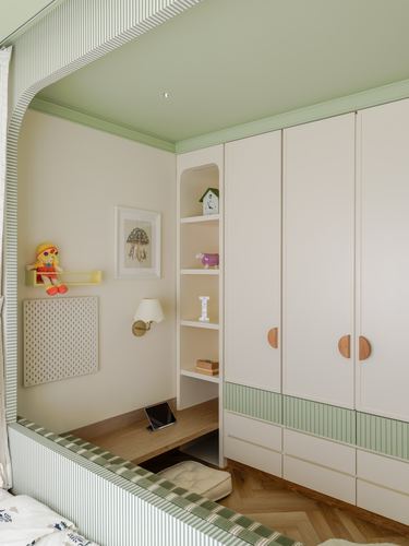 Child's bedroom with sage-green ceiling, cream wardrobes with wooden handles, and an arched bookshelf niche
