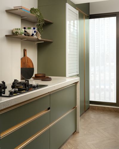 Olive green kitchen counter with brass trim, stone countertop, open wood shelves, and herringbone floor