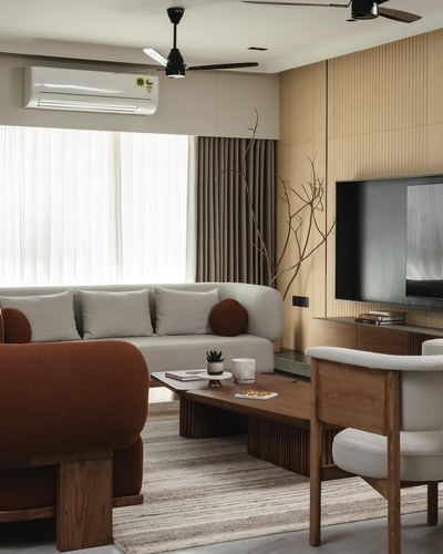 Living room with rust sofa, beige sectional, wood coffee table and fluted panel tv wall